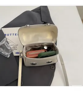 Vue détaillée de l'intérieur d'un mini sac carré crème contenant des objets essentiels