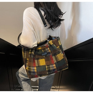 Detail of multi-color plaid tote bag with black leather strap and metal chain accents