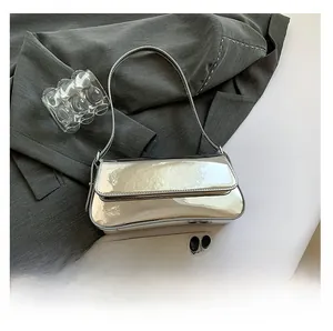 Detailed close-up of glossy silver patent leather shoulder bag with magnetic flap closure