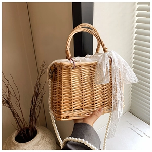 Detail of hand-woven straw basket bag with white lace bow and large pearl handle strap