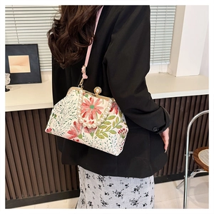 Detail of floral embroidery and pearl handle on a retro off-white crossbody bag