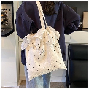 Detail of white floral tote bag featuring ruffled edges and Magic Pocket label