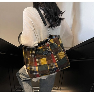 Detailed view of colorful checkered tote bag featuring leather chain strap on a model