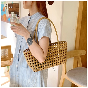 Detail shot of handwoven straw bag featuring hollow geometric textures and long handles