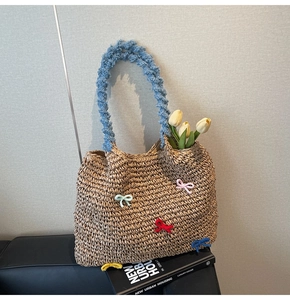 Detail of straw woven tote bag with colorful crochet bows and soft blue plush handles