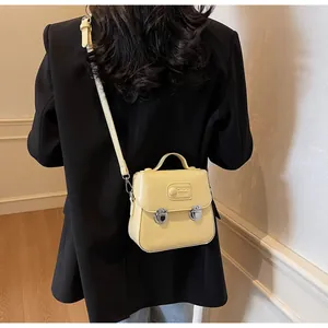 Détail d'un sac à bandoulière en cuir synthétique jaune pâle avec logo embossé et boutons