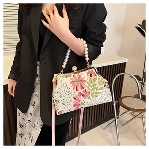 Detailed embroidery of floral patterns and luxury pearl handle on retro handbag