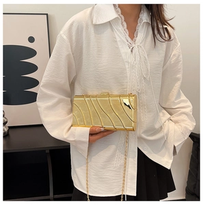 Close-up of golden evening clutch featuring wave texture and metallic chain strap