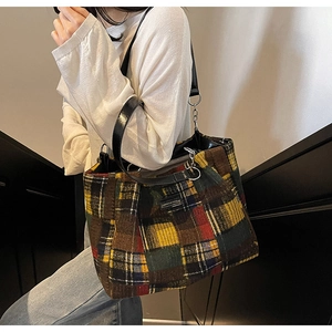 Close-up of multicolor plaid tote bag with leather handles and silver chain detail