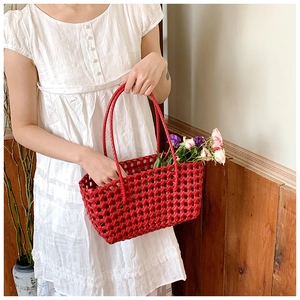 Detail of red hollow woven handbag with flowers against a white polka dot dress