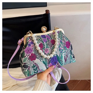 Detail of vintage floral fabric bag with large pearl handle and metal clasp closure