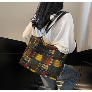 Detailed view of a multi-color plaid tote bag with leather straps on a model's shoulder