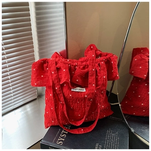 Detail of red floral tote bag with ruffle trim and woven label on a book background