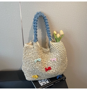 Detail of straw tote bag featuring colorful knit bows and soft faux fur blue handles