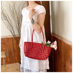 Close-up of bright red woven tote bag used as a floral basket with fresh roses