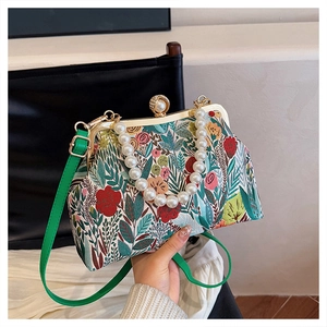 Detailed view of vintage floral fabric handbag with large pearl handle and green strap
