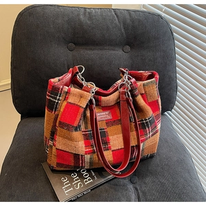 Detail view of red-brown plaid tote bag with faux leather handles and metal hardware