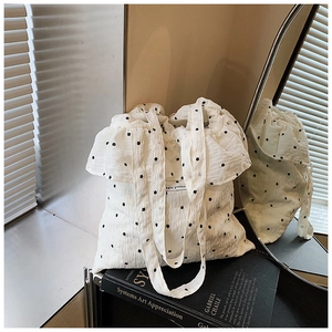 Close-up of white floral tote bag with simple pocket label and wavy ruffle edges