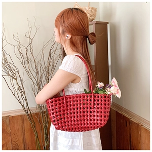 Detail of red woven bucket bag with elegant long handles showing craftsmanship and texture