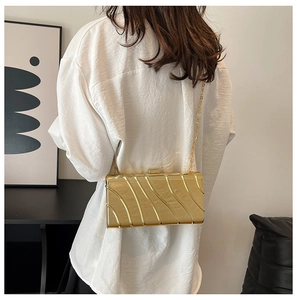 Dettaglio di una borsa a mano dorata con texture a onde verticali e sottile tracolla