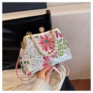 Detail of floral embroidery on vintage handbag with large pearl clasp and gold frame
