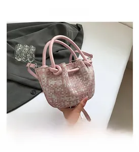 Detailed view of pink woven plaid bucket bag featuring a unique knotted round handle