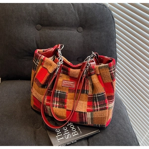 Close-up of contrast color tweed tote bag with red leather handles and metallic chain details