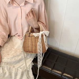 Retro straw bucket bag with white lace bow and pearl strap worn by a model