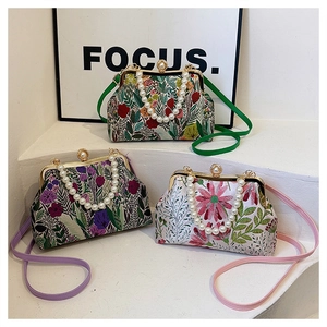 Detailed embroidery on vintage kiss-lock bags with pearl handles and floral patterns