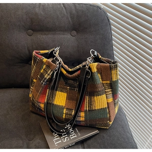 Macro detail of multicolored plaid fabric texture and black leather strap on tote bag