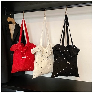 Three-color polka dot tote bags with ruffle trim and Magic Pocket label hanging on a rack