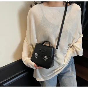 Détail d'un mini sac noir à bandoulière avec boucles argentées et poignée élégante