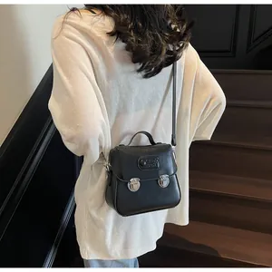 Détail d'un petit sac carré noir mat vintage avec boucles argentées sur l'escalier