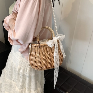 Retro handmade straw bucket bag with lace bow and pearl strap shown on shoulder