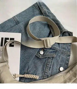 Detail of khaki nylon half-moon crossbody bag with woven zipper pull and adjustable strap