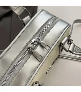Detailed close-up of smooth silver metallic dual zippers and hardware logo on the handbag