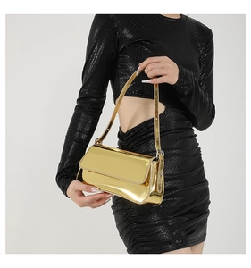 Detail of glossy gold metallic handbag with mirror finish and slim shoulder strap