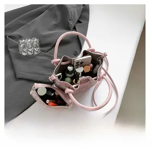Pink tweed bucket bag with top handle showing interior capacity for phone and cosmetics