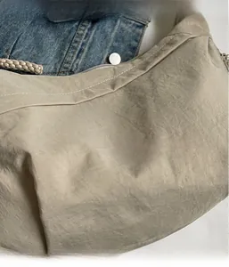 Detailed macro view of beige nylon dumpling bag with stitching and rope handle