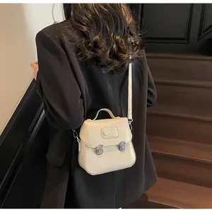 Détail du sac bandoulière crème avec boucles argentées sur une veste de costume noire