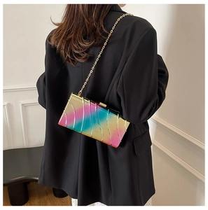 Dettaglio borsa box in acrilico arcobaleno con catena dorata su blazer nero
