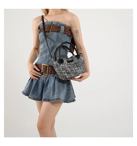 Detail of woven bucket bag featuring grey mosaic texture and black leather drawstrings