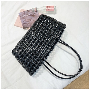Detail of black woven leather tote bag with wide strap hollow weave and square texture