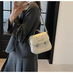 Détail du mini sac carré blanc perle avec doubles boucles en métal et écusson