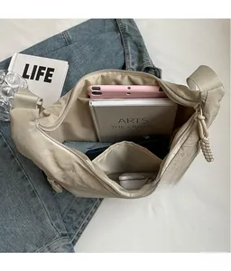 Detail view of large beige nylon crossbody bag interior holding a tablet and books