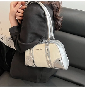 Detail view of contrast color Boston bag featuring silver metal leather and circular logo tag