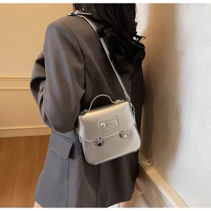 Détail d'un sac bandoulière argent mat avec double fermoir et poignée supérieure fine