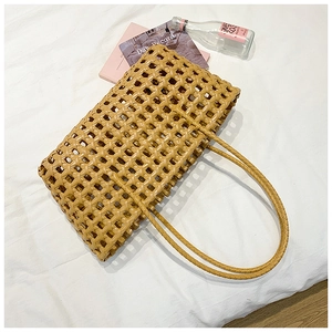 Detailed view of hollow woven tote bag in camel color on elegant white fabric background