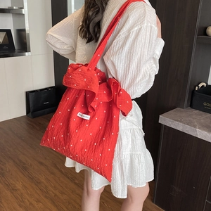 Minimalist red floral canvas tote bag with a large side bow detail worn by a model