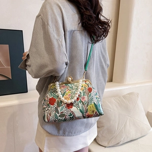 Vintage floral crossbody bag with pearl handle and green strap shown on a model